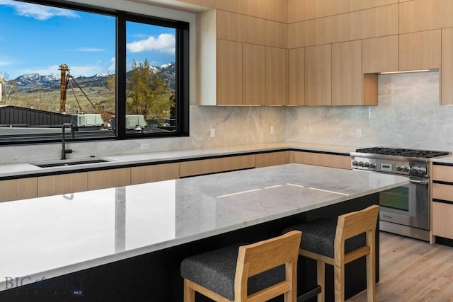 kitchen with a kitchen bar, modern cabinets, high end range, and a sink