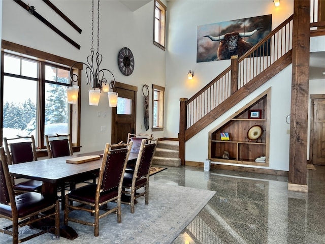 dining room featuring a chandelier, built in features, and a towering ceiling