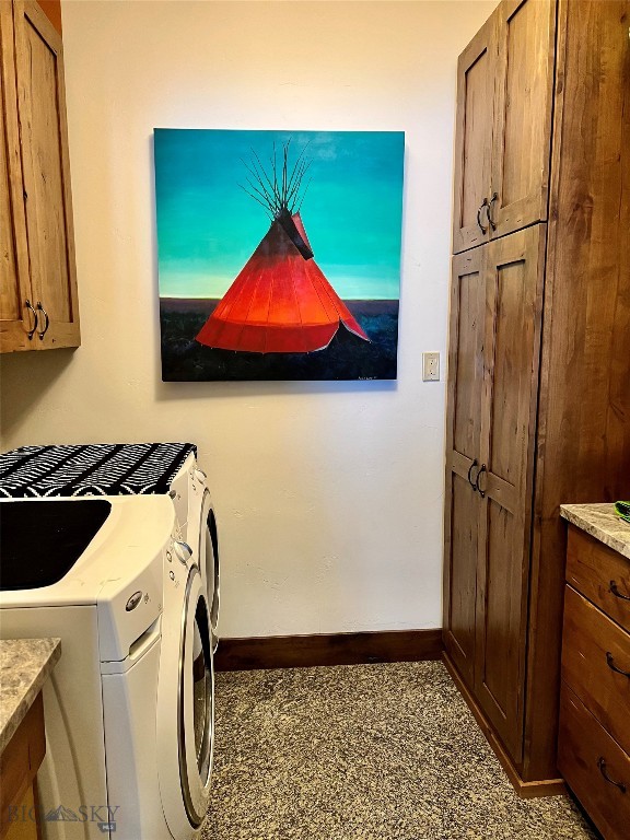 clothes washing area featuring cabinets and washer and clothes dryer