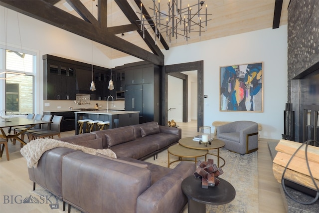 living room with high vaulted ceiling, sink, light hardwood / wood-style flooring, beam ceiling, and a chandelier