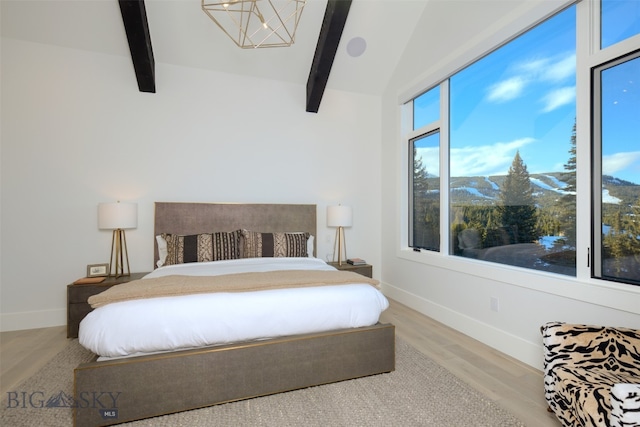 bedroom featuring hardwood / wood-style flooring, lofted ceiling with beams, and an inviting chandelier