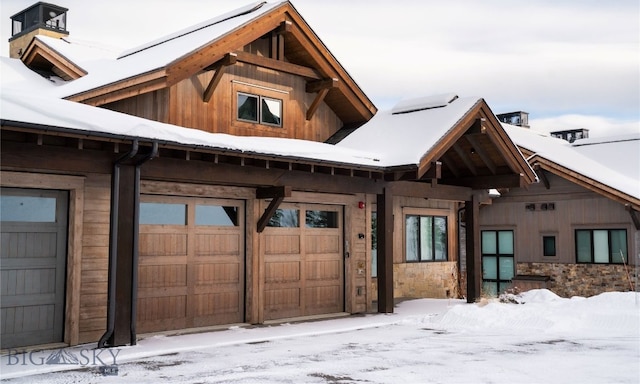 snow covered back of property with a garage