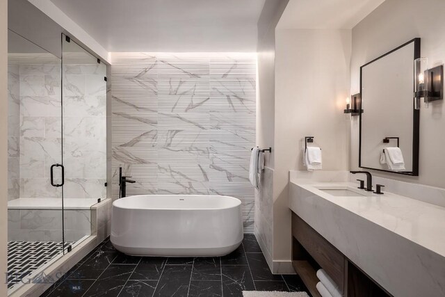 bathroom with marble finish floor, tile walls, a freestanding bath, a stall shower, and vanity