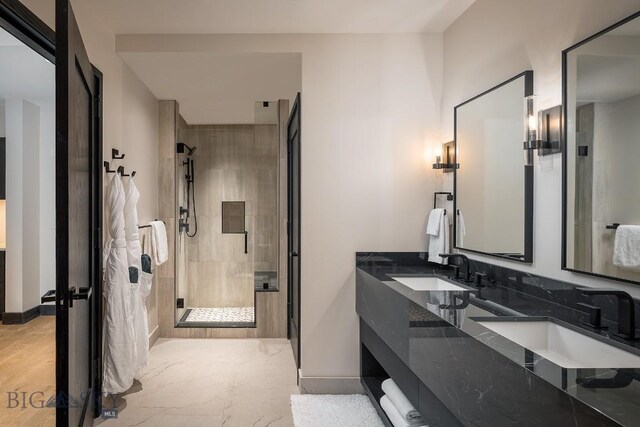 full bath with double vanity, a stall shower, baseboards, and a sink