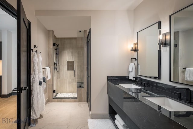 full bathroom featuring a stall shower, a sink, baseboards, and double vanity