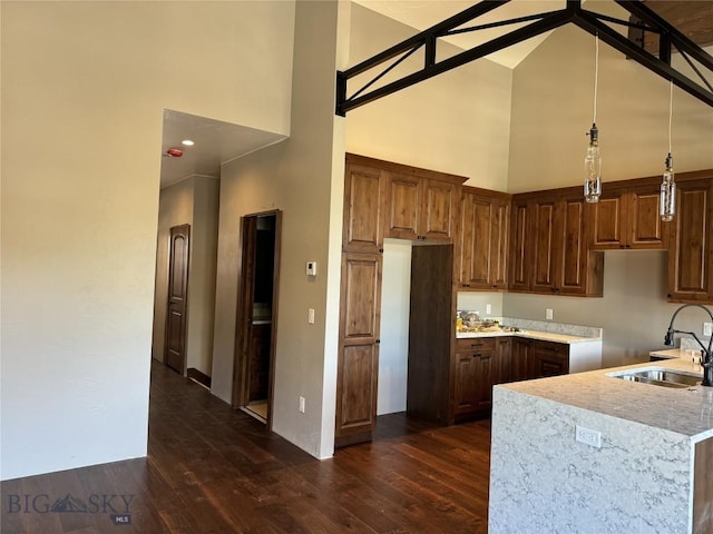 kitchen with pendant lighting, high vaulted ceiling, dark wood-type flooring, and sink