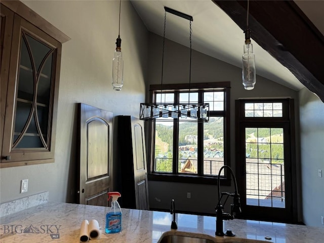 kitchen with vaulted ceiling, decorative light fixtures, a chandelier, and sink