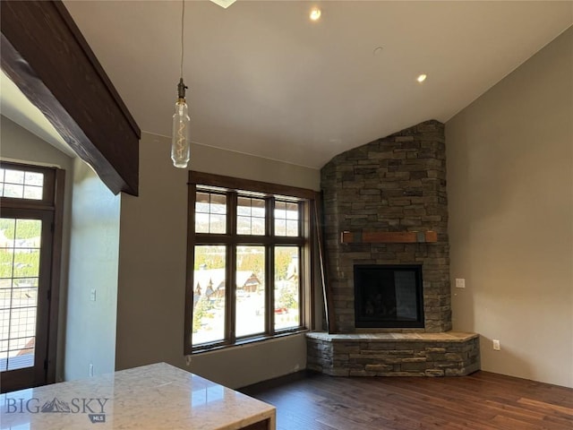 unfurnished living room with dark hardwood / wood-style floors, a stone fireplace, and vaulted ceiling