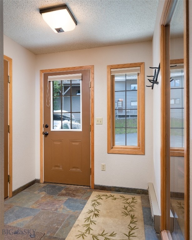 interior space with dark tile flooring, a textured ceiling, and a healthy amount of sunlight