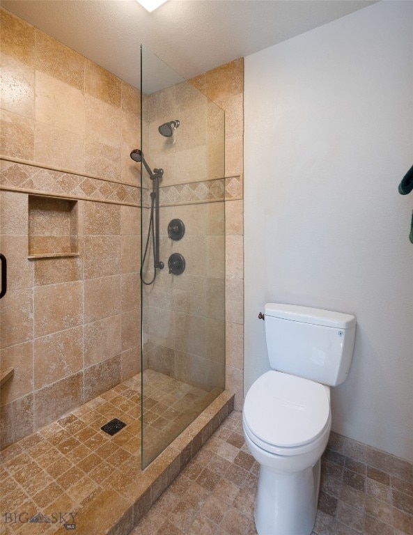 bathroom featuring toilet, tile flooring, and tiled shower