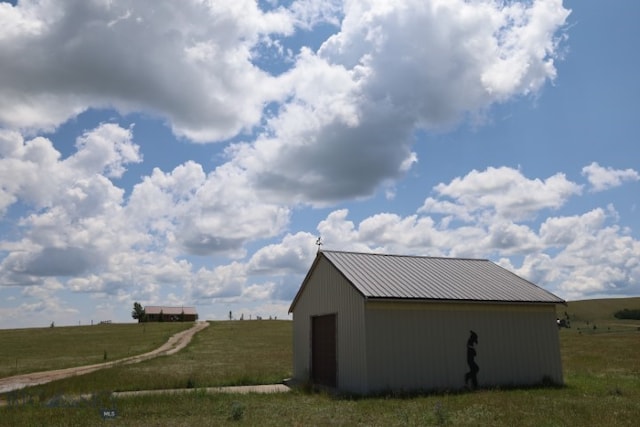 view of side of property featuring an outdoor structure and a rural view