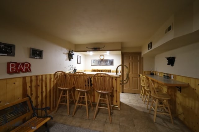 dining area with bar area and light tile floors