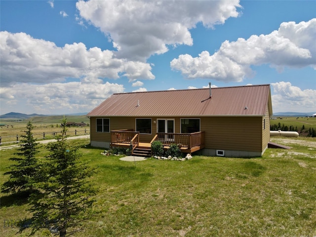 back of property featuring a deck, a rural view, and a lawn