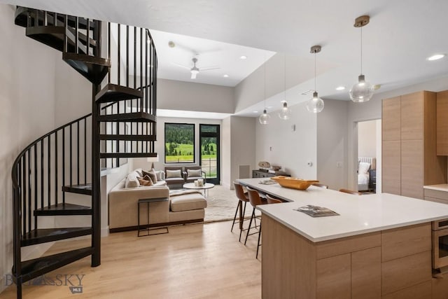 kitchen featuring ceiling fan, a center island, light hardwood / wood-style floors, and decorative light fixtures