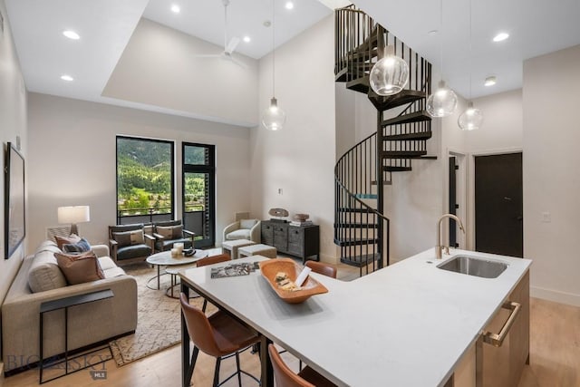 kitchen featuring a kitchen island with sink, sink, and hanging light fixtures