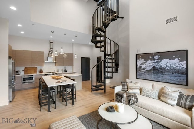 living room with light hardwood / wood-style floors and a towering ceiling