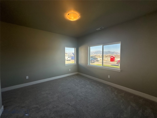 carpeted empty room featuring vaulted ceiling and a mountain view