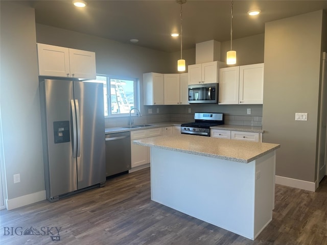 kitchen featuring stainless steel appliances, pendant lighting, white cabinets, and sink