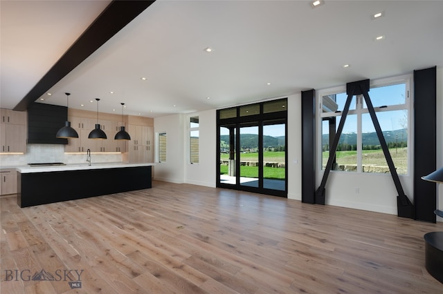 kitchen with an island with sink, decorative light fixtures, a healthy amount of sunlight, and backsplash