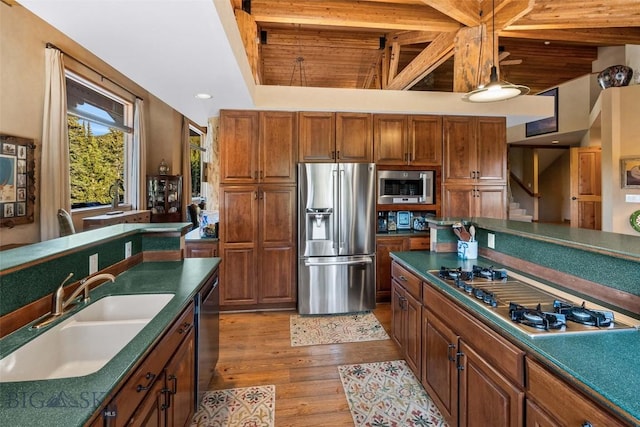 kitchen featuring dark countertops, appliances with stainless steel finishes, wood finished floors, and a sink