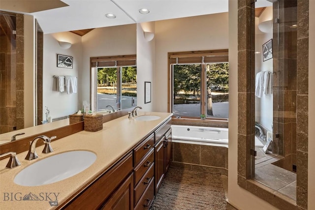 bathroom with a bath, recessed lighting, double vanity, and a sink