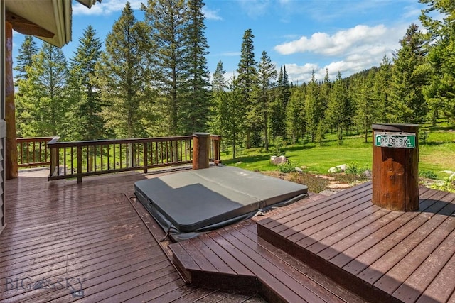 wooden deck with a covered hot tub, a yard, and a view of trees