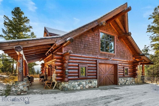 view of side of property featuring a garage, a barn, log exterior, and an outdoor structure