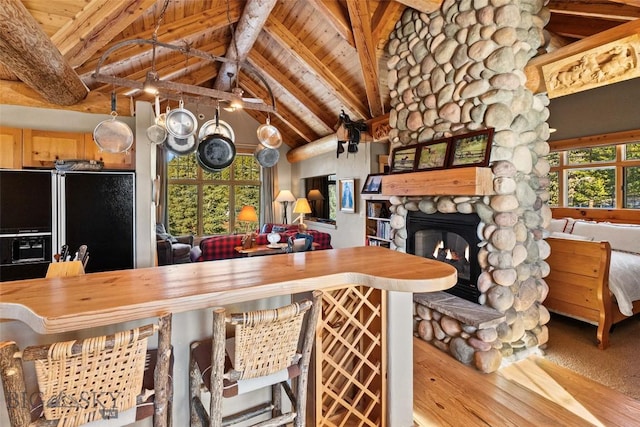 kitchen featuring a stone fireplace, wooden ceiling, beamed ceiling, and open floor plan