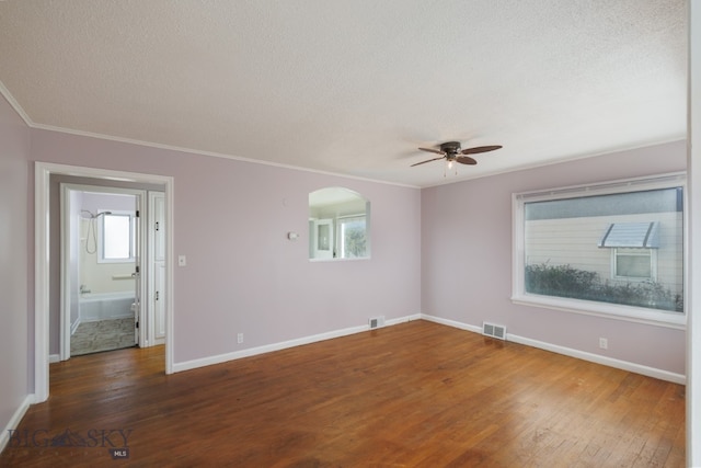 empty room featuring ceiling fan, a textured ceiling, ornamental molding, and dark hardwood / wood-style floors