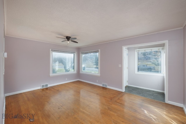 spare room with light hardwood / wood-style flooring, ceiling fan, plenty of natural light, and a textured ceiling