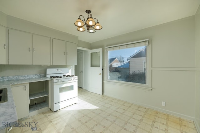 kitchen with an inviting chandelier, light stone countertops, white range with gas cooktop, and light tile flooring