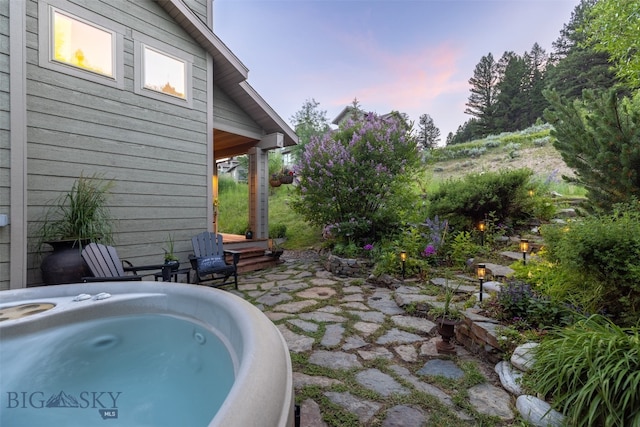 pool at dusk with a patio and a hot tub