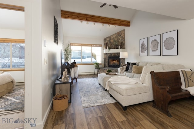 living room with vaulted ceiling with beams, dark hardwood / wood-style floors, a stone fireplace, and ceiling fan