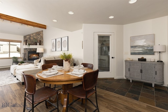 dining space with lofted ceiling with beams, dark hardwood / wood-style flooring, and a fireplace