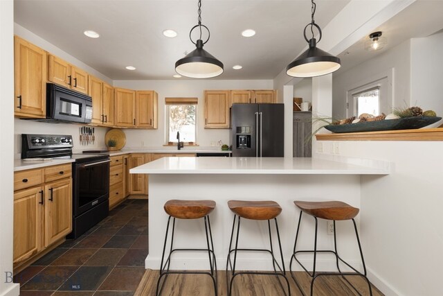 kitchen featuring a kitchen bar, decorative light fixtures, kitchen peninsula, and black appliances