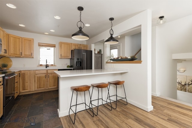 kitchen featuring kitchen peninsula, hardwood / wood-style floors, black electric range oven, and high end fridge