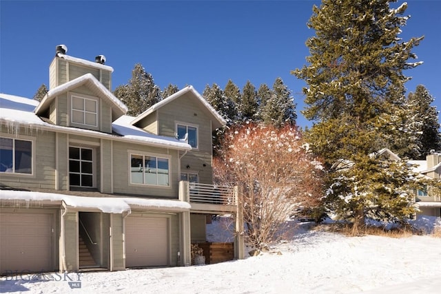 snow covered back of property with a garage