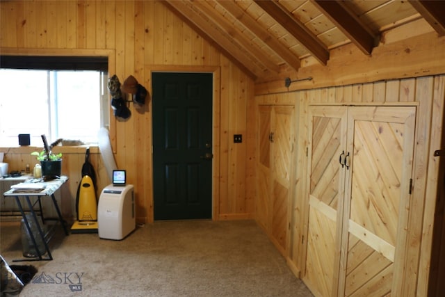 interior space featuring vaulted ceiling with beams, light colored carpet, wood walls, and wooden ceiling