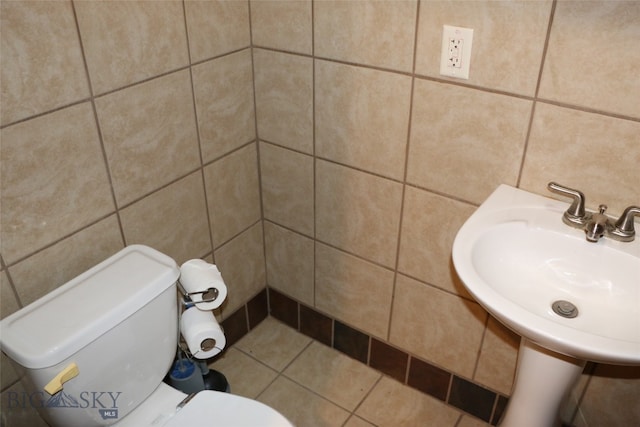 bathroom featuring tile walls, tile patterned flooring, toilet, and sink