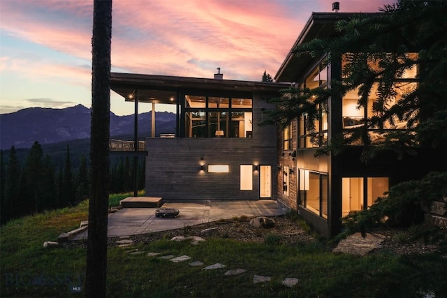 back of property at dusk featuring a patio and a mountain view