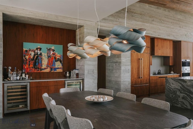 dining room with beverage cooler, a bar, and dark wood finished floors