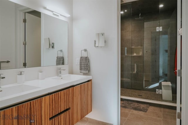 bathroom featuring a stall shower, tile patterned flooring, a sink, and double vanity