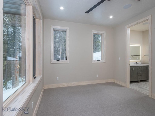 unfurnished bedroom with light carpet, ensuite bathroom, ceiling fan, and sink