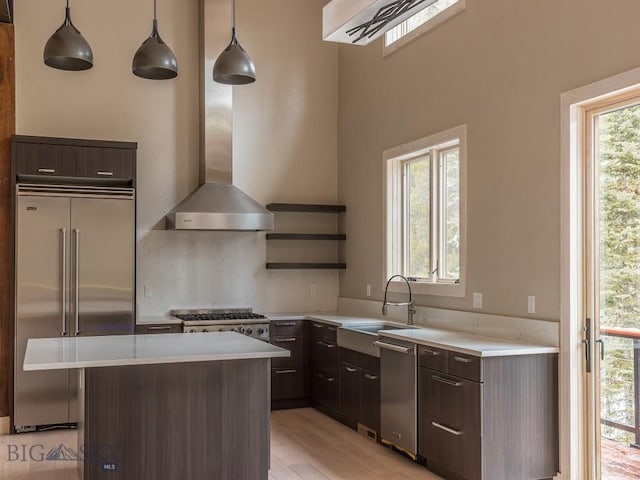 kitchen with stainless steel appliances, sink, light hardwood / wood-style flooring, a center island, and hanging light fixtures