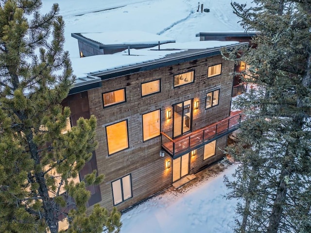 snow covered house featuring a balcony