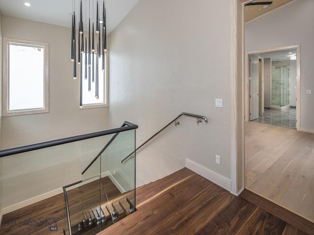 stairway with vaulted ceiling and hardwood / wood-style flooring