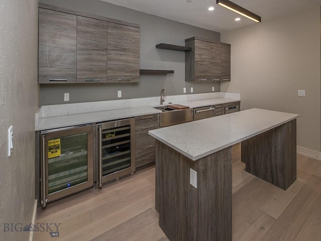 kitchen featuring light wood-type flooring, a center island, and beverage cooler