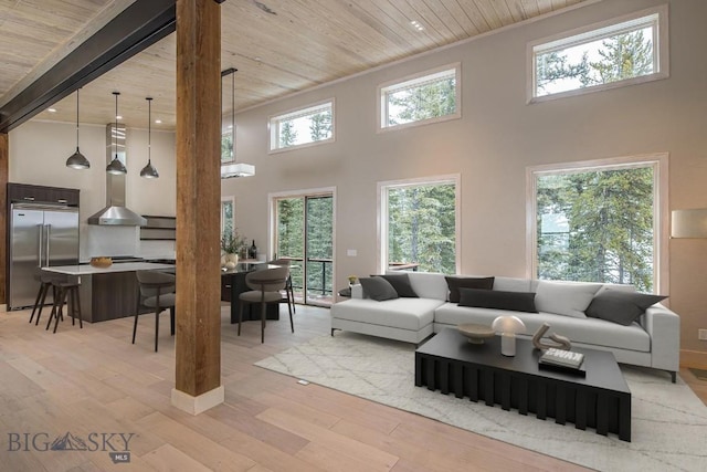 living room featuring a high ceiling, light wood-type flooring, wooden ceiling, and beam ceiling