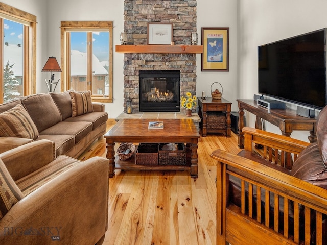 living room with a stone fireplace and light wood-type flooring