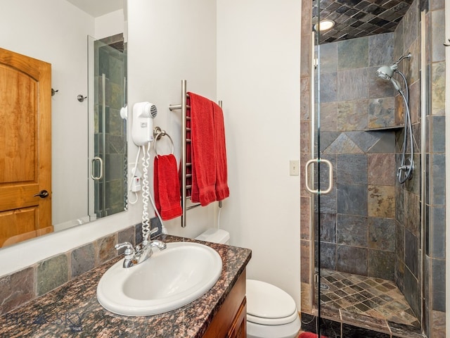 bathroom with toilet, large vanity, and an enclosed shower